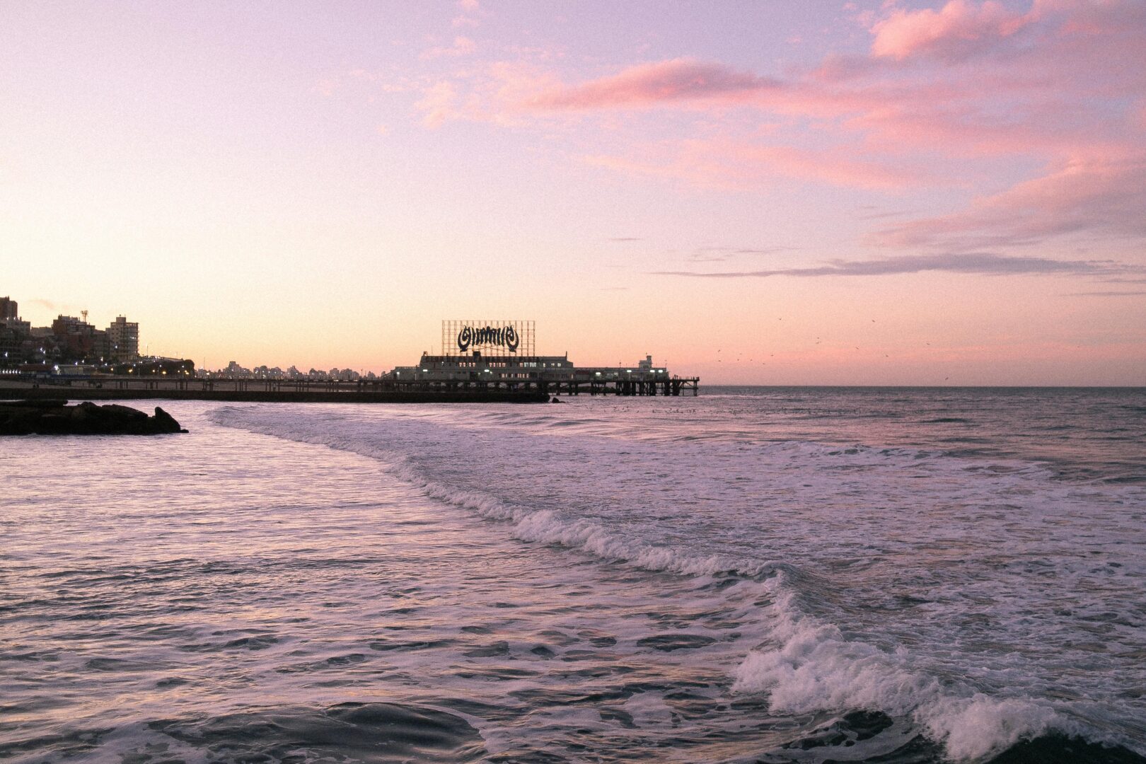 Beautiful sunset view at Mar del Plata beach, Argentina with ocean waves and pier silhouette.